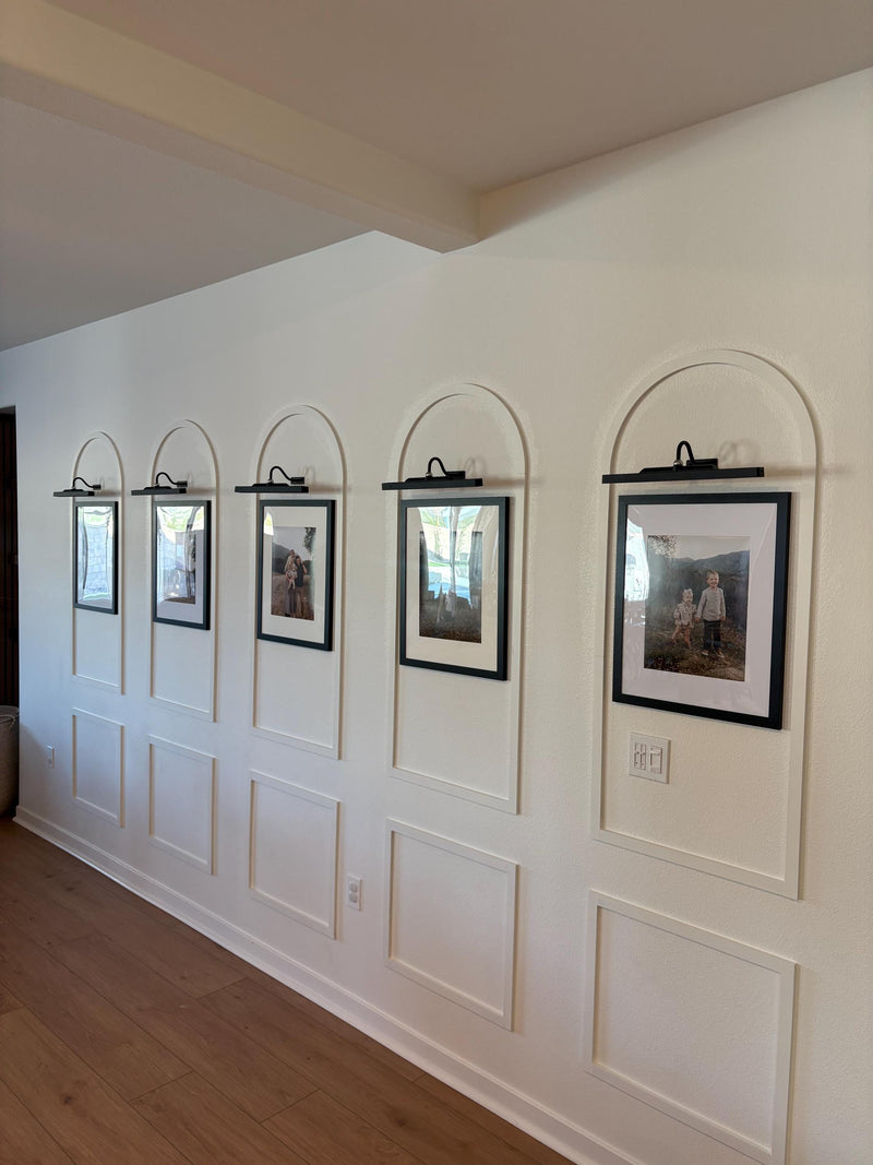 real home accent wall created with DIY arched MDF wall molding trim kit-Row of framed pictures on a wall with paneling