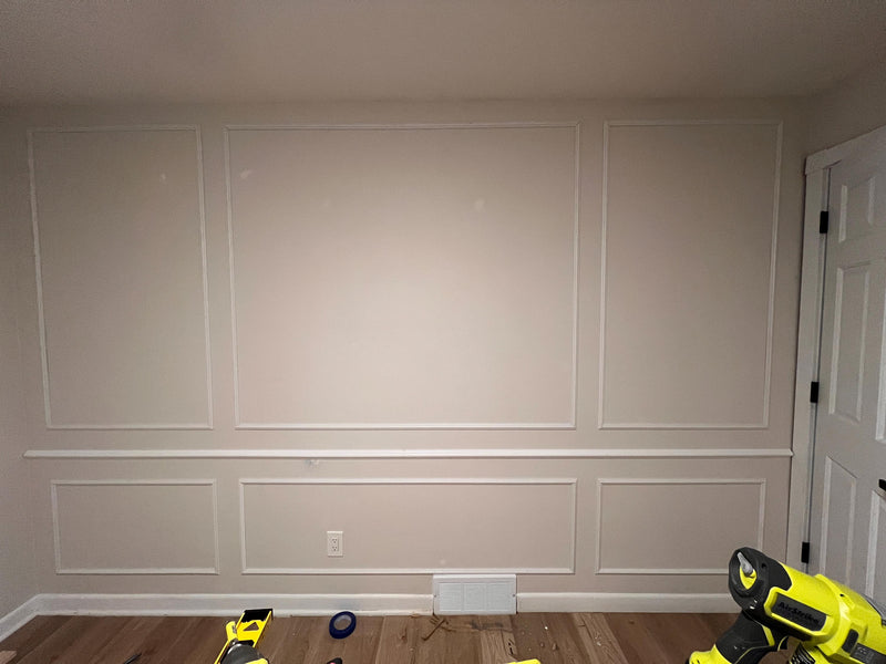 DIY picture frame wall molding panel design completed in modern living room-Wall with paneling and tools on a wooden floor