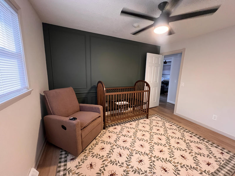 DIY picture frame wall molding panel design completed in modern living room-Nursery room with a brown recliner chair and wooden crib.