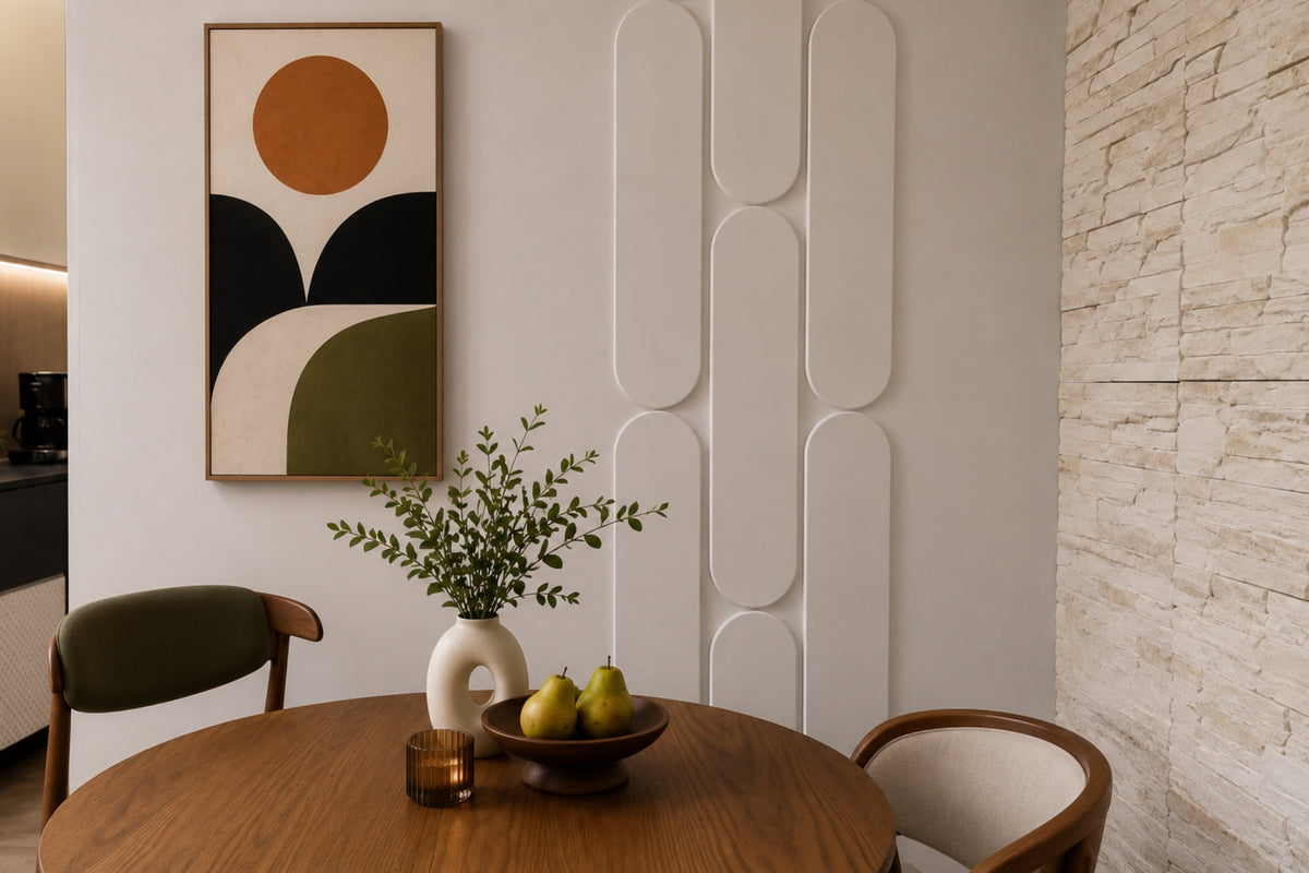 A styled interior dining corner featuring a round wooden table with chairs, a white vase with greenery, and a bowl of pears, set against a wall with abstract geometric wall art and textured paneling.