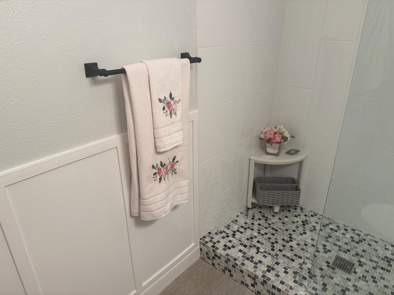 customer installed shaker-board and batten wall molding kit showing finished panel wall design-Bathroom corner with towels on a rack, small table with flowers, and tiled floor.