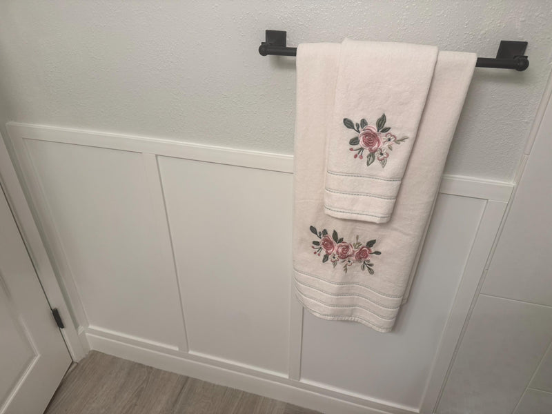 customer installed shaker board and batten wall molding kit showing finished panel wall design-Towels with floral embroidery hanging on a towel rack against a white wall.