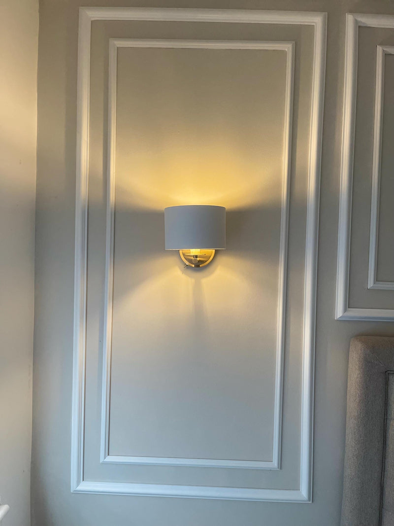 Wall-mounted light fixture on a gray wall with decorative molding.
