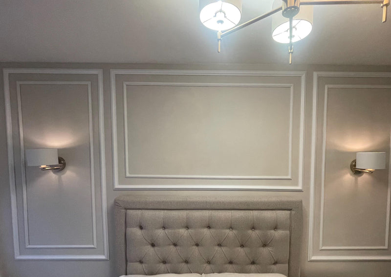 Neatly decorated bedroom with a tufted headboard and decorative wall molding design.