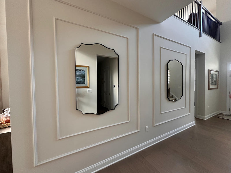  decorative wall molding panels creating an elegant accent wall-Two mirrors on a wall with decorative molding in a room.