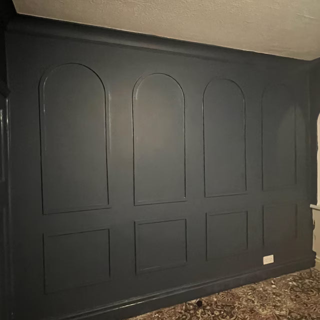real home accent wall created with DIY wall molding trim kit-Dark gray paneling with arched and rectangular cutouts on a wall.