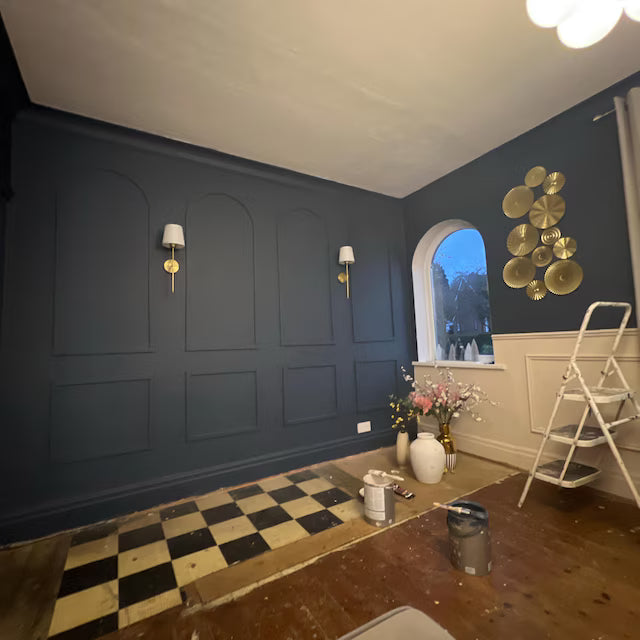 real home accent wall created with DIY wall molding trim kit-Room with dark blue walls, a checkered floor, and decorative elements.