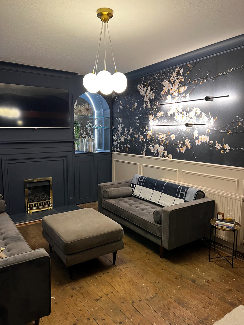 real home accent wall created with DIY wall molding trim kit-Living room with gray sofa, ottoman, and decorative wall art.